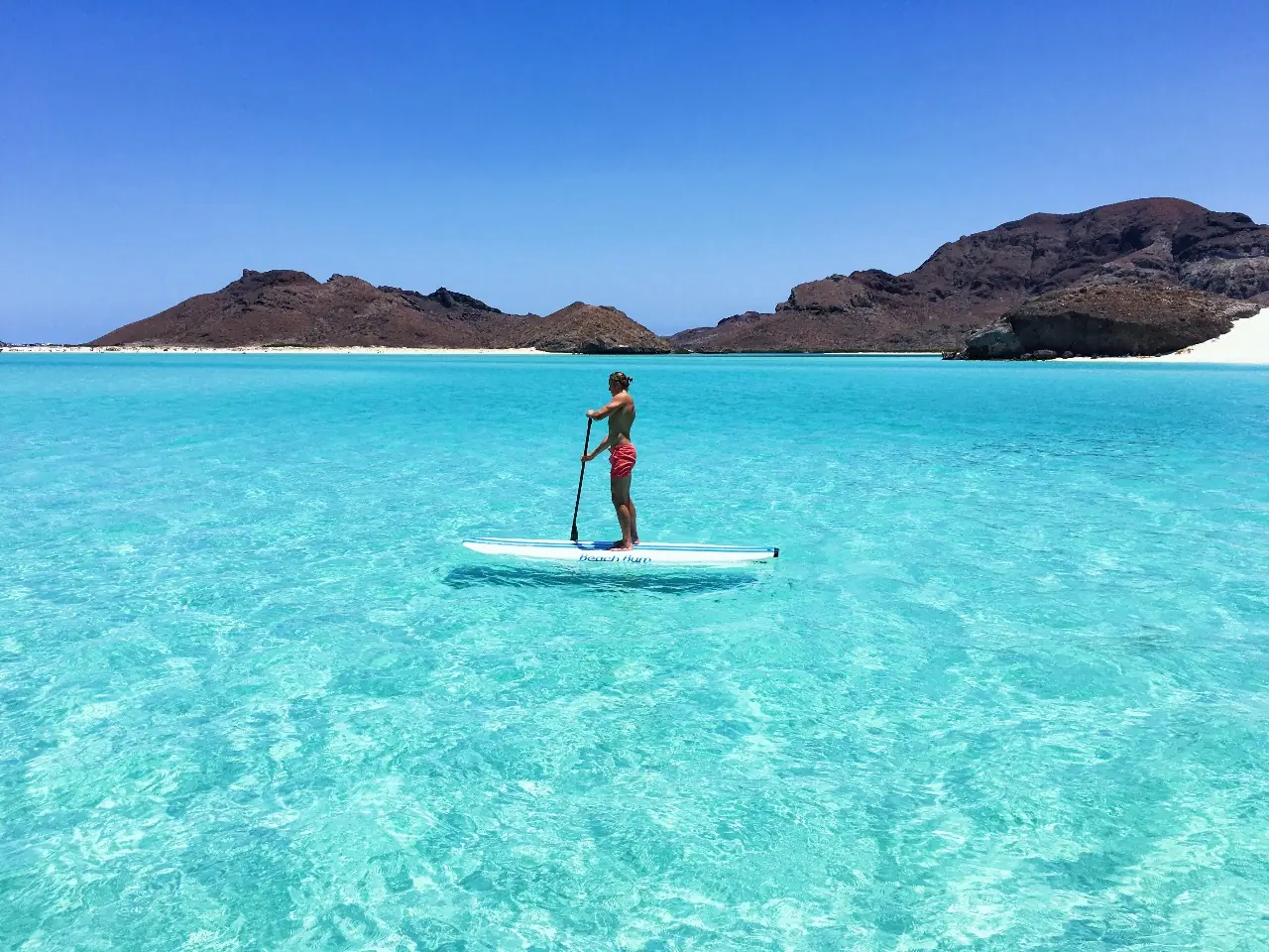 Honeymoon Package 20 Paddleboarding on flat turquoise water off an island beach near La Paz